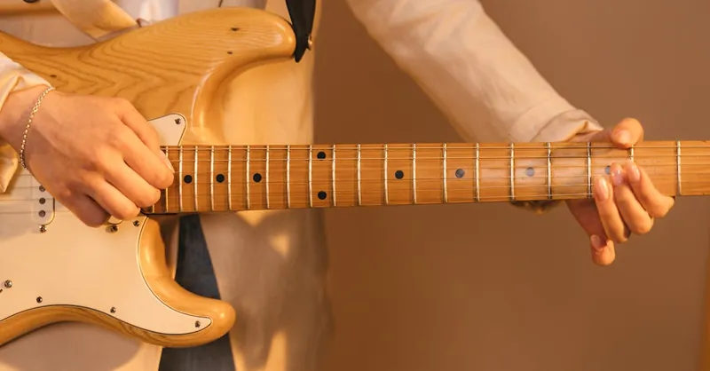 A detailed close-up of hands strumming an electric guitar, showcasing technique.