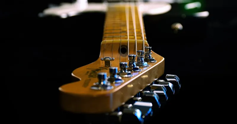 Artistic close-up of an electric guitar showing strings and tuners, highlighting depth and craftsmanship.