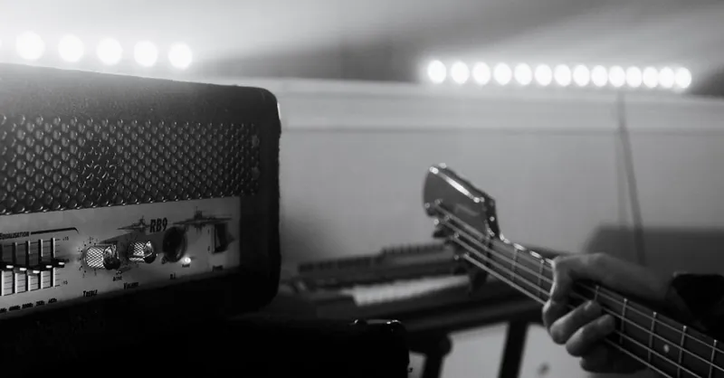 Black and white close-up of bass guitar with amplifier, capturing musical vibe in studio.