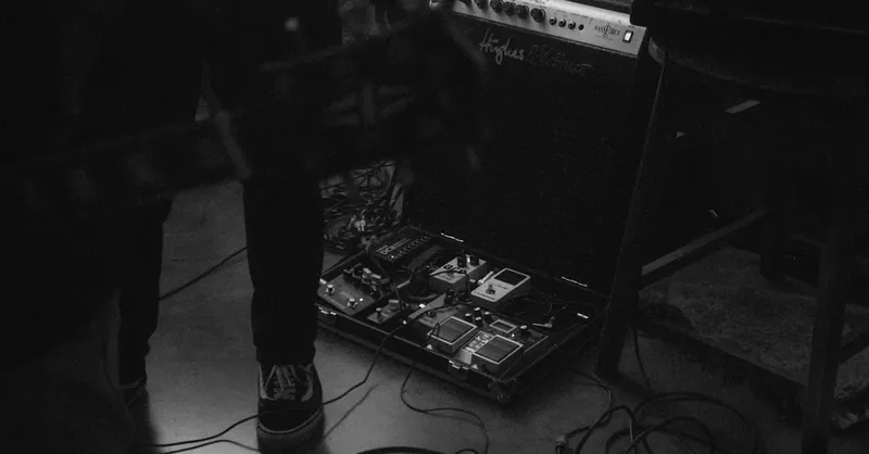 Black and white photo of a guitar setup with effects pedals, perfect for music enthusiasts.