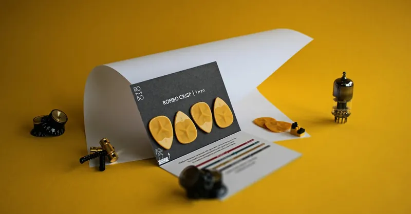 Yellow guitar picks and amp components artistically arranged on paper for a product showcase.