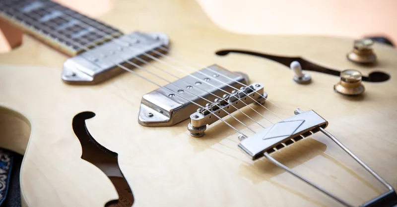Detailed close-up of a wooden electric guitar showing strings and body parts.