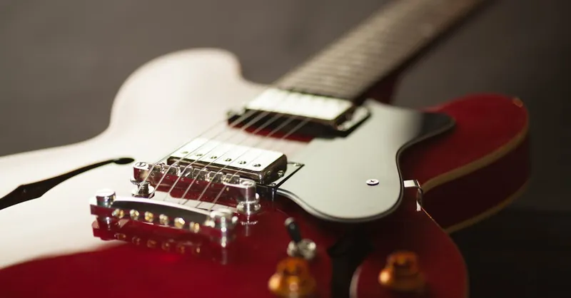 Detailed close-up of a red electric guitar showcasing the bridge and strings.