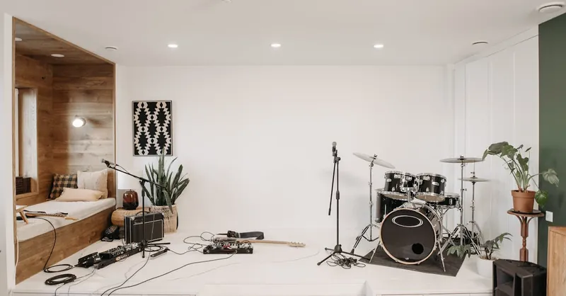 A modern music studio featuring a drum set, guitar, and cozy seating area for musicians.
