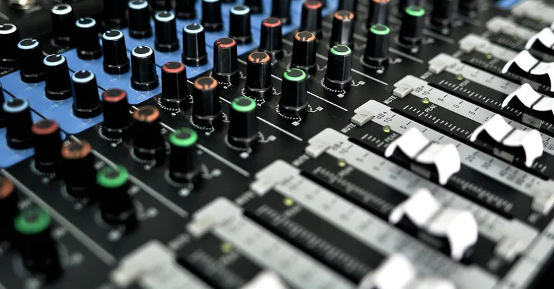Detailed view of a professional audio mixing console with knobs and sliders for sound control.