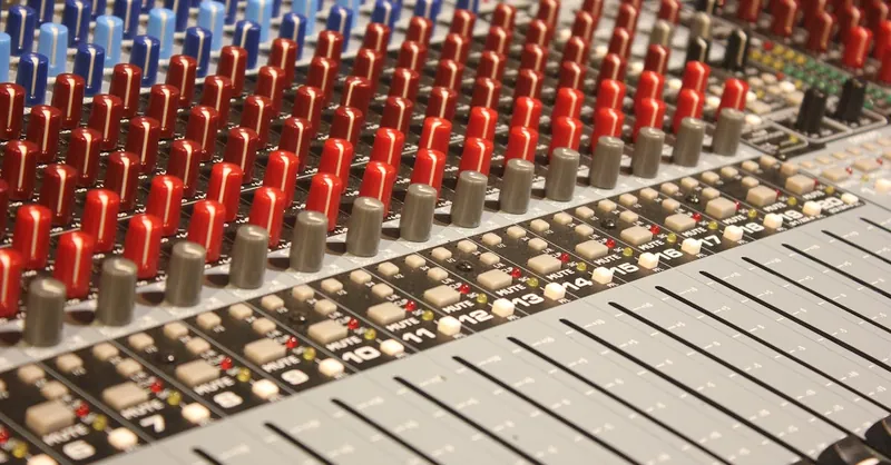 Close-up of audio mixing console with red and blue knobs, ideal for music production.