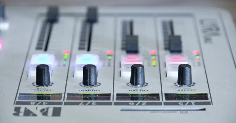 Detailed view of an audio mixer with knobs and control sliders for sound adjustment.