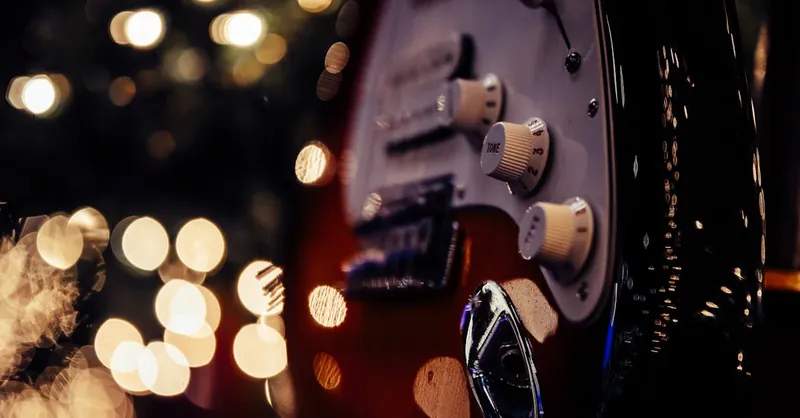 Detailed close-up of an electric guitar highlighting its tone controls and bokeh lights.
