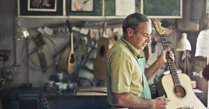 A skilled luthier works on an acoustic guitar in a well-organized workshop.