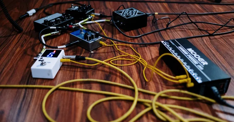 Close-up view of audio equipment and cables arranged on a wooden floor.