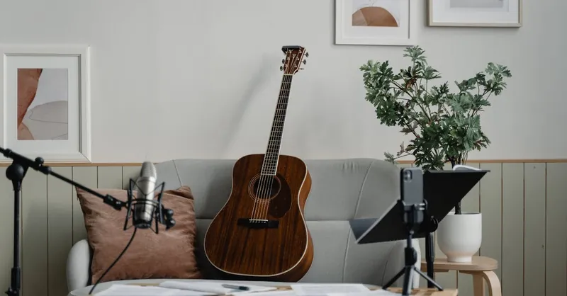 A peaceful home music studio with a guitar, microphone, and indoor plant setup for recording.