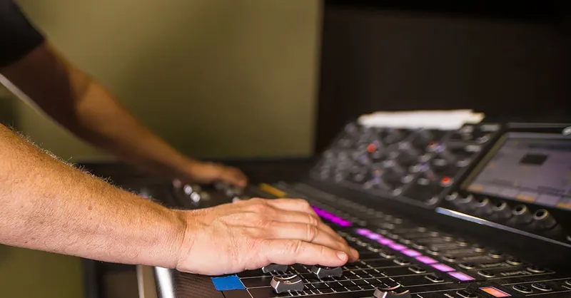 Hands of a sound engineer adjusting levels on an audio mixer in a professional recording studio.