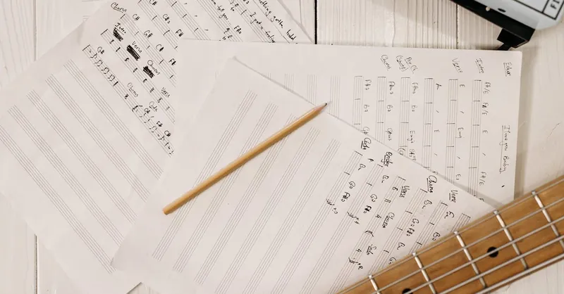 Close-up view of sheet music, a guitar, and a pencil, ideal for music creation and inspiration.