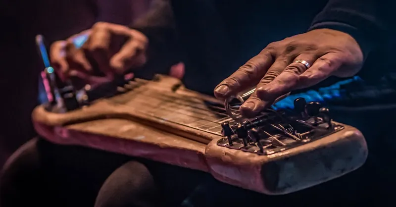 Detailed shot of a musician playing a vintage lap steel guitar with a slide and ring.