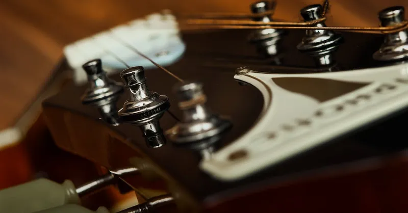 Extreme close-up of a guitar headstock, focusing on the strings and tuners.